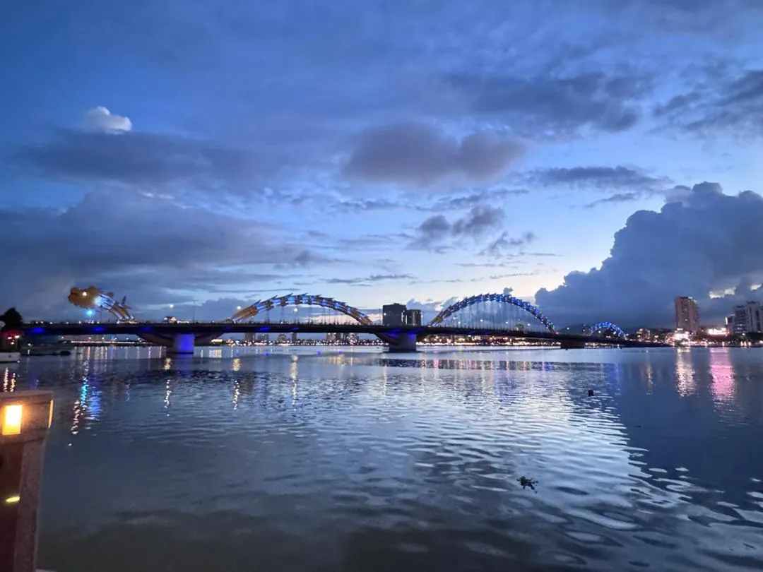 Dragon Bridge in Da Nang lit up across the river at dusk
